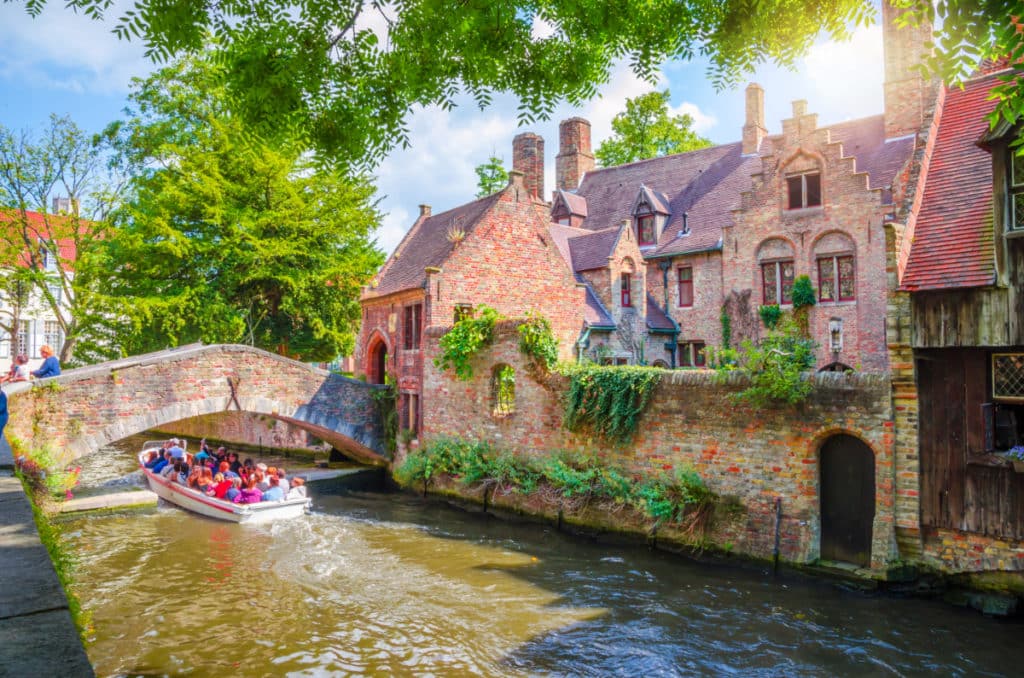 villes de belgique à visiter, ici sur la photo Bruges, avec le canal et un bateau, maisons typiques